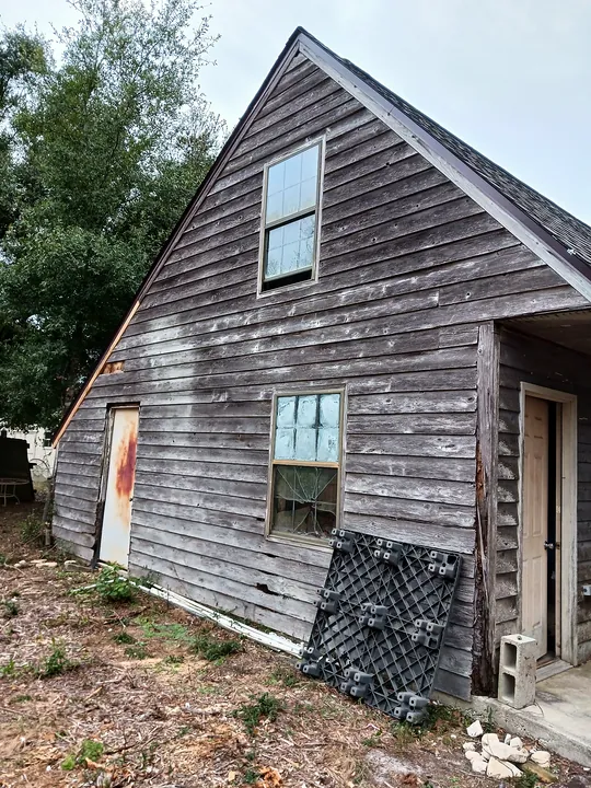 Before: weathered, rotting wood siding on a two-story outbuilding