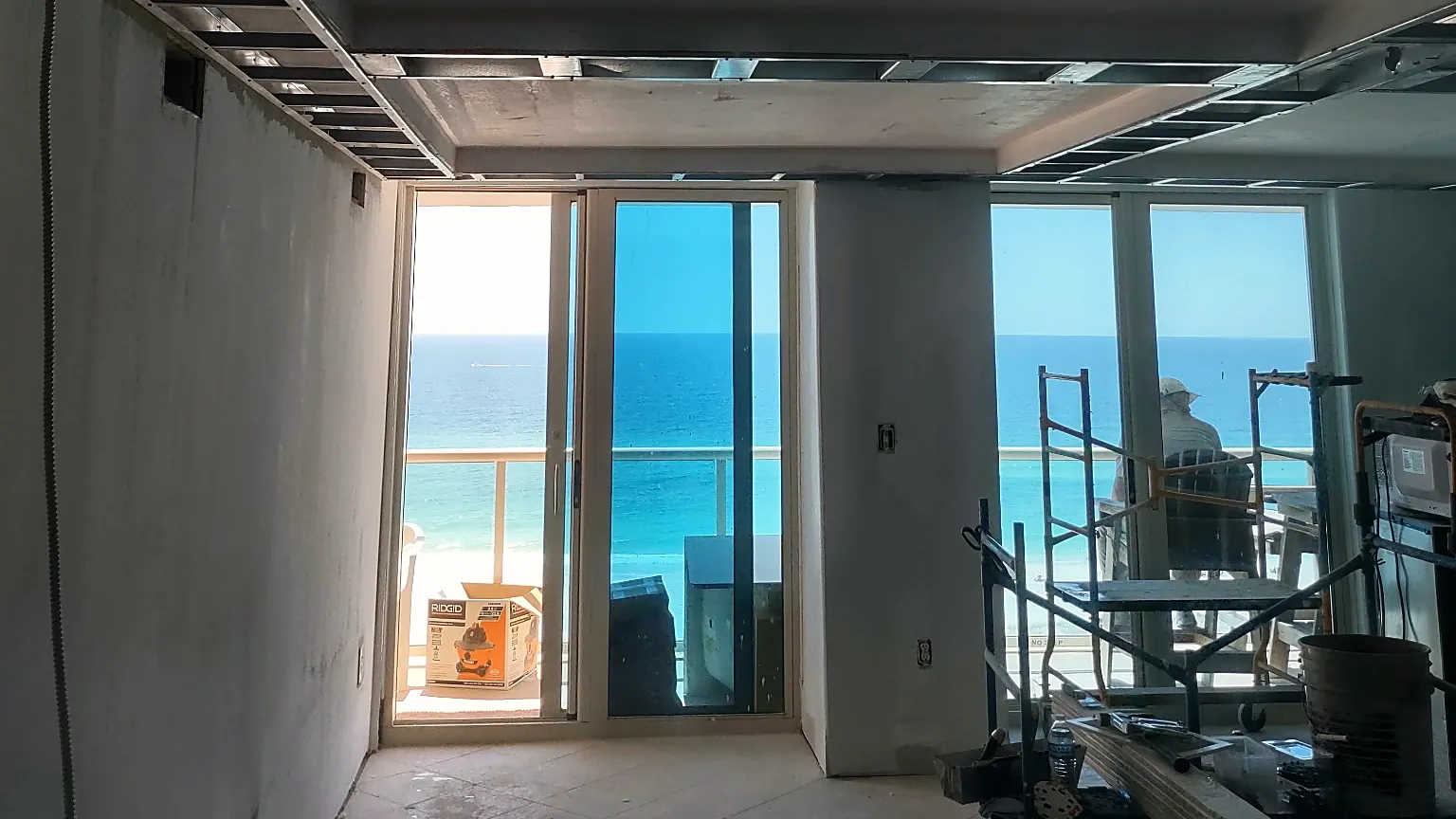 Gulf-front condo mid-remodel with new ceiling framing and Gulf views through the balcony doors